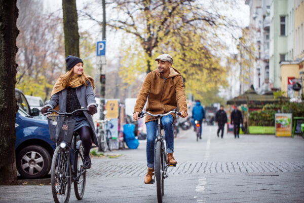 Smiling Friends Cycling On City Street In Winter